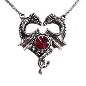 May include: A silver necklace with a heart-shaped pendant featuring two intertwined dragons with a red gemstone in the center.
