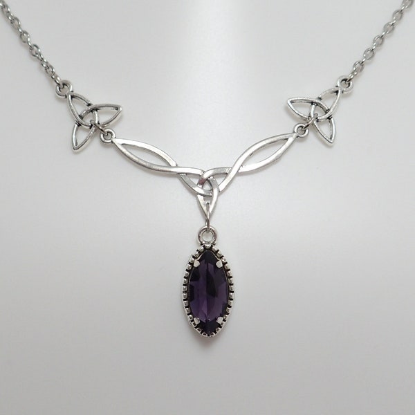 Op de afbeelding: Een zilveren ketting met een Keltisch knoopontwerp en een hanger met een paarse edelsteen. De ketting heeft een delicate ketting en twee Keltische knoopontwerpen aan weerszijden van de hanger.