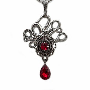 May include: Silver octopus pendant necklace with a large red gemstone in the center and a smaller red teardrop gemstone hanging below.