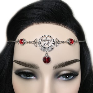 May include: Silver headband with a pentagram charm and red crystal accents. The headband is adorned with a Celtic knot design.