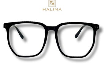 May include: Black square-framed eyeglasses with clear lenses. The glasses have a thick frame and a subtle textured pattern. The brand name "HALIMA" is displayed in gold lettering above the glasses.