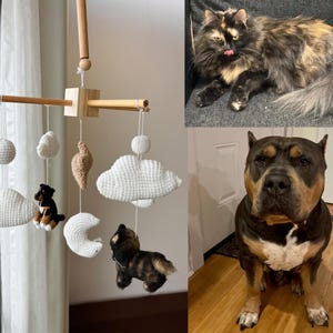 Op de afbeelding: Een houten babymobiel met gehaakte witte wolken, een witte maan, een beige ster en twee kleine gehaakte honden. De mobiel hangt aan een houten dwarsbalk. Daarnaast staan twee foto's van een schildpadkat en een hond.