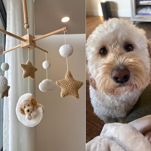 May include: A wooden baby mobile with crocheted clouds, stars, and a crescent moon with a small crocheted dog inside. The mobile is hanging from a wooden frame.