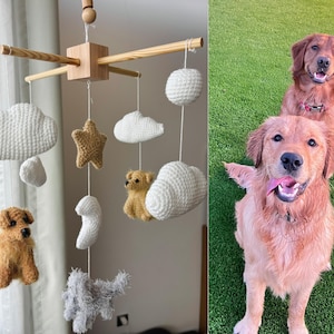 Op de afbeelding: Een hangende mobiel met een houten kruisframe, witte gehaakte wolken, een beige gehaakte ster, een beige gehaakte beer, een witte gehaakte maan en twee kleine gehaakte honden in beige en grijs, naast twee golden retriever honden.