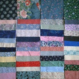 May include: A collection of fabric squares in various colors and patterns, including floral, paisley, and geometric designs. The squares are arranged in rows, creating a patchwork effect.