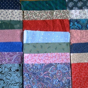 May include: A collection of fabric swatches in various colors and patterns. The swatches include floral, paisley, and geometric designs in shades of blue, red, pink, green, and purple. The fabrics are arranged in neat rows.