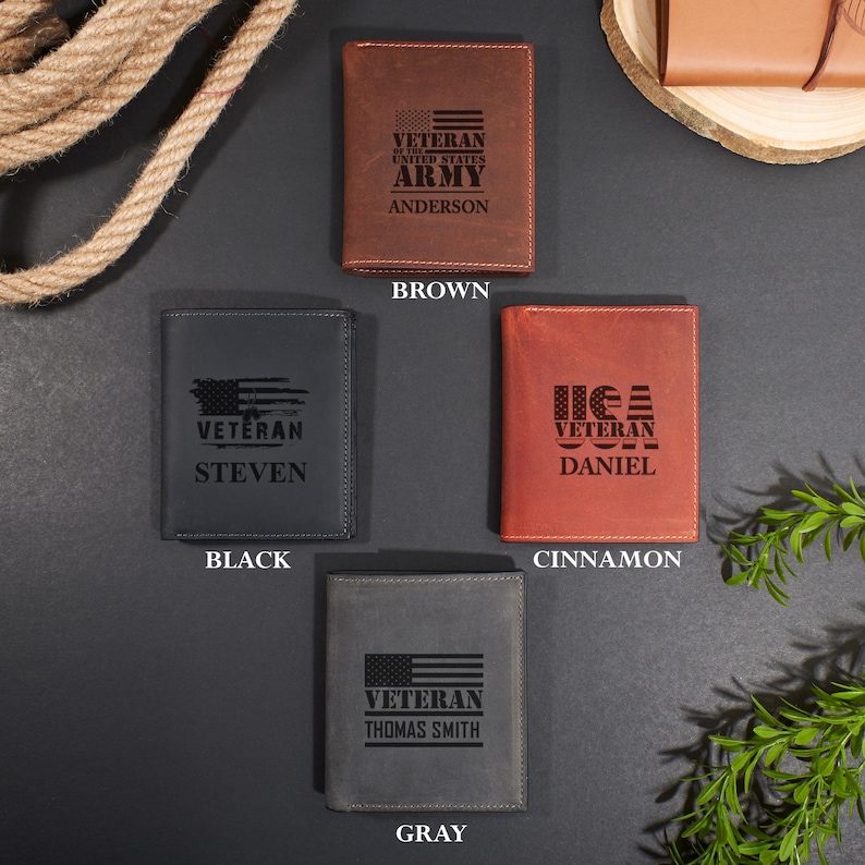 May include: Four rectangular leather wallets in brown, black, cinnamon, and gray. Each wallet features a laser-engraved design including an American flag motif, the word VETERAN, and a personalized name: ANDERSON, STEVEN, DANIEL, or THOMAS SMITH.