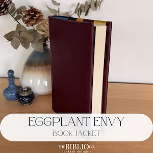 May include: A hardback book featuring a deep burgundy, leather-textured book jacket. The spine is accented with a gold-coloured band at the top. The pages are cream-coloured, and the interior lining visible at the top edge is a bright blue colour.