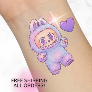 Puede incluir: Tatuaje temporal colorido con un personaje de dibujos animados con un disfraz de conejito peludo, un coraz&oacute;n morado y un efecto de explosi&oacute;n estelar. El personaje tiene una expresi&oacute;n traviesa y es en tonos morado, rosa y azul.