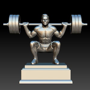 May include: A silver-colored statue of a weightlifter in a squat position, holding a barbell with weights. The statue is on a rectangular base, set against a black background. The figure is muscular and detailed, showcasing the form of a weightlifter.