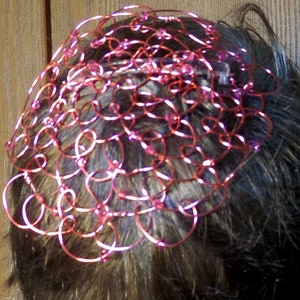 May include: A pink wire hair crown with pink beads woven into the wire.
