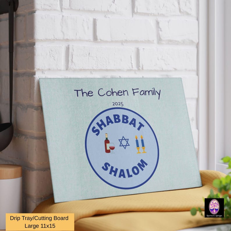 May include: A blue and white cutting board with the text "The Cohen Family 2025" and a blue circle with the text "Shabbat Shalom" and a Star of David, wine bottle, and candles inside.