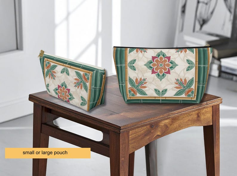 K&ouml;nnte beinhalten: Zwei dekorative Beutel mit floralen Mustern. Die Beutel haben einen cremefarbenen Hintergrund mit einem sich wiederholenden Design aus Blumen und Bl&auml;ttern in Orange-, Rosa- und Gr&uuml;nt&ouml;nen. Die R&auml;nder sind mit gr&uuml;nen und goldenen Akzenten versehen. Sie werden auf einem Holztisch ausgestellt.