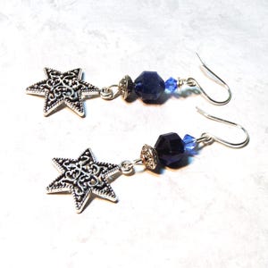 Image is of a pair of earrings with Star of David vintage charms. The dangling gemstones are bicone crystals, sodalite half rounds and a silvertone spacer.