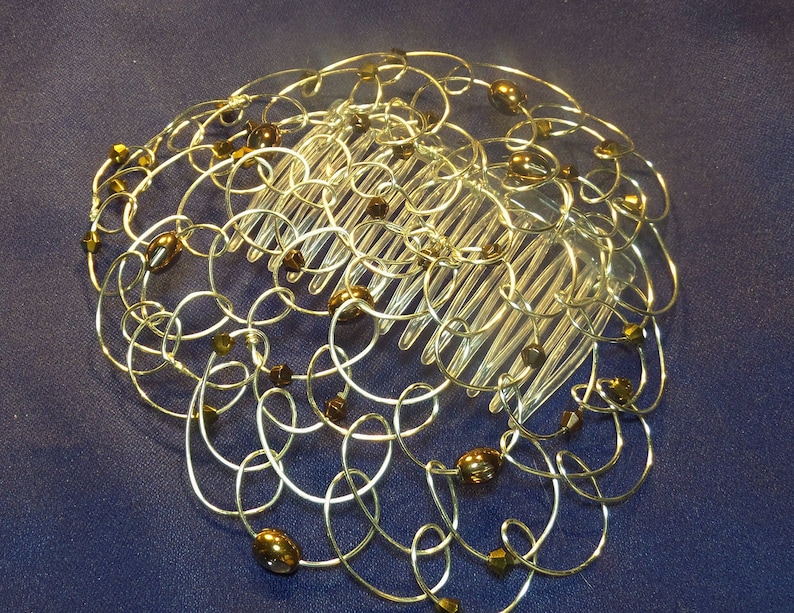 Image is of a handmade wire wrapped beaded wire kippah with copper oval beads and a plastic comb on a dark background.