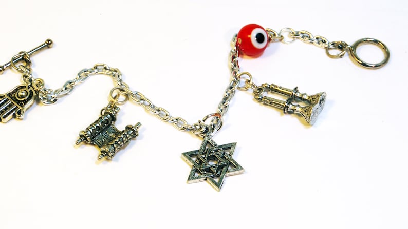 Photo of silver Jewish charm bracelet including hamsa, torah, star of david, shabbat charm & toggle clasp