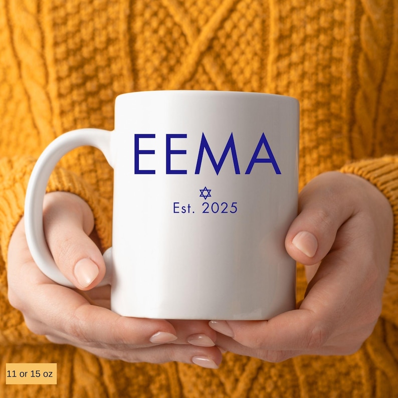 May include: A white ceramic mug with a blue inscription that reads 'EEMA Est. 2025' and a blue Star of David symbol.