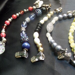 May include: Five beaded chains with silver clips. The chains feature different colored beads, including red, blue, white, gray, and yellow. The chains are all about 18 inches long.
