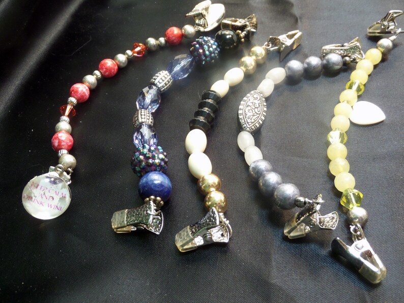 May include: Five beaded chains with silver clips. The chains feature different colored beads, including red, blue, white, gray, and yellow. The chains are all about 18 inches long.