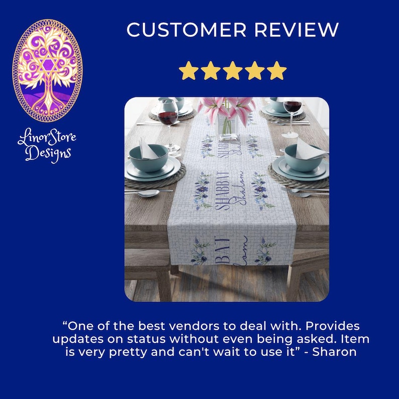 Op de afbeelding: Een rechthoekige tafelloper met bloemen- en tekstdetails, geplaatst op een houten tafel. De loper bevat de woorden "Shabbat Shalom" en "Bat" in een decoratief lettertype, met blauwe bloemaccenten. De tafel is gedekt met kommen, borden en wijnglazen.