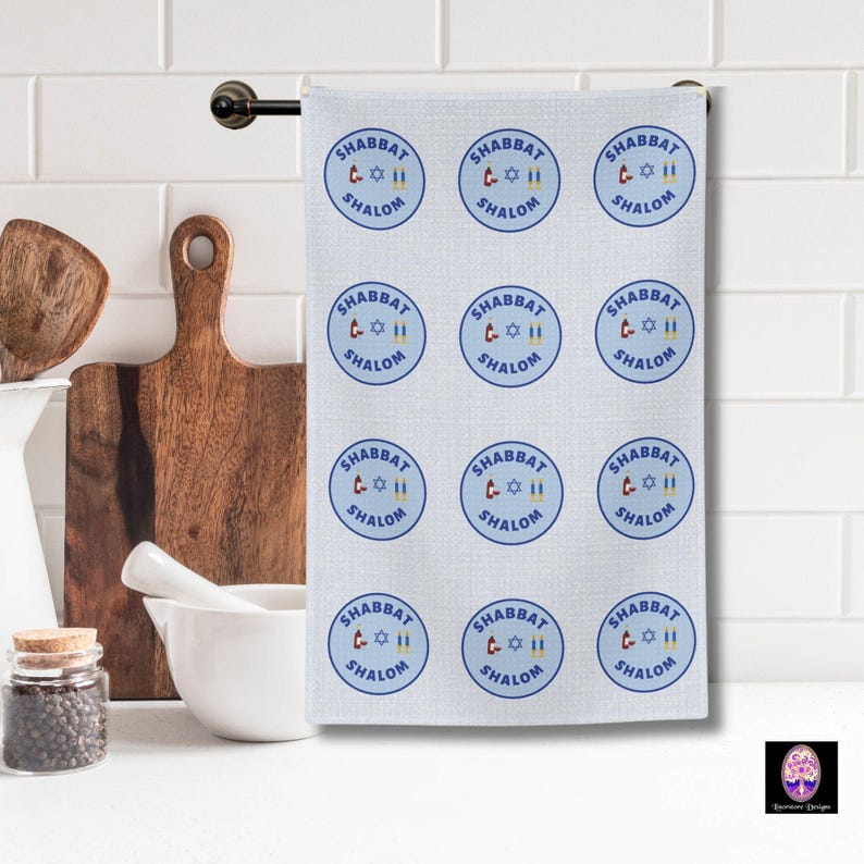 May include: A white kitchen towel with a blue and white pattern of repeated circles. Each circle contains the text "Shabbat Shalom" and a graphic of a Star of David and two candles.