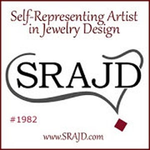 May include: A white background features the text "Self-Representing Artist in Jewelry Design" in burgundy. The logo "SRAJ D" is in black, with a stylized grey line. Below is "#1982" and the website address www.SRAJ D.com.