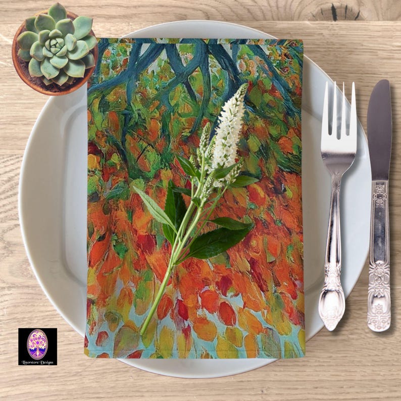 May include: A white dinner plate with a colorful napkin with a floral design. The napkin has a blue, green, orange, and yellow design with white flowers. The napkin is placed on the plate with a silver fork and knife to the right of the plate.