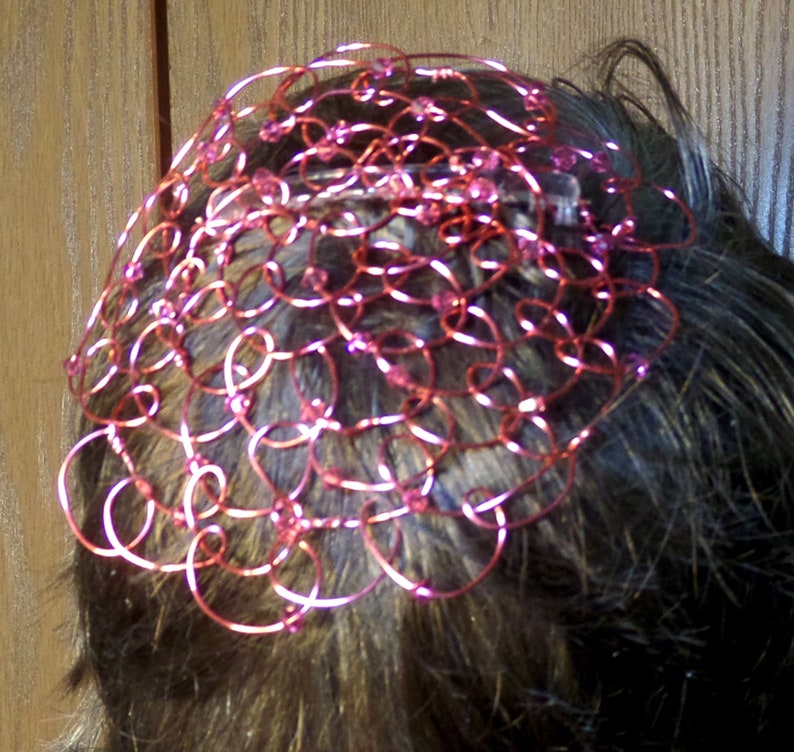 May include: A pink wire hair crown with pink beads woven into the wire.