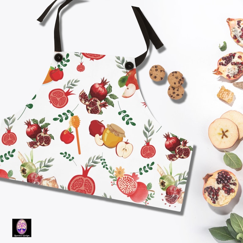 An image of a patterned apron with pomegranates, and apples and honey on a holiday background.