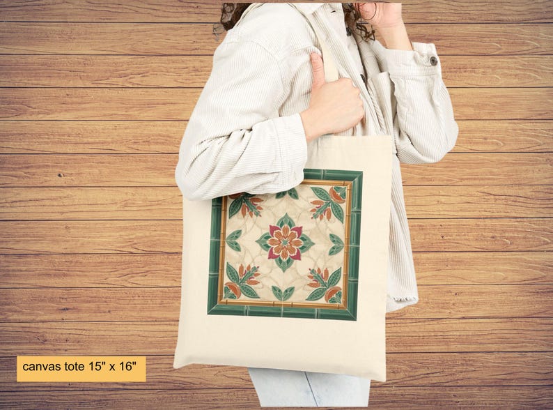 K&ouml;nnte beinhalten: Leinwand-Tragetasche, 38 cm x 41 cm, mit einem quadratischen Blumendesign und einem gr&uuml;nen Rand. Das Design umfasst die Farben Orange, Gr&uuml;n und Creme. Die Tasche besteht aus hellem Canvas-Material.