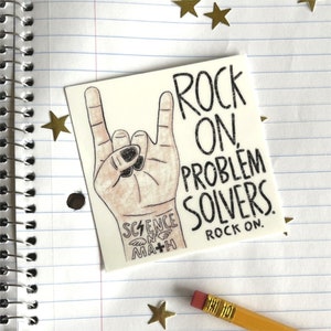 May include: A white sticker with a hand making the rock and roll hand gesture. The sticker says "Rock On Problem Solvers. Rock On." and has a small graphic that says "Science + Math".