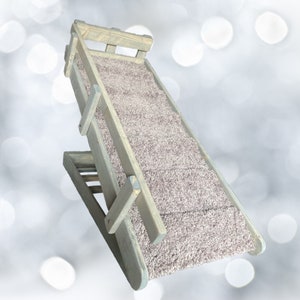 May include: A wooden pet ramp with a gray stain and a light pink carpet surface. The ramp is angled and has a railing on the side.