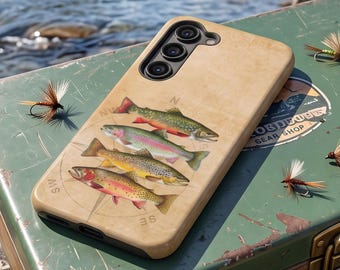May include: A tan smartphone case featuring a detailed illustration of four different trout species arranged vertically, with a faint compass rose design in the background. The case has a cutout for a triple-lens camera system on the upper left corner.