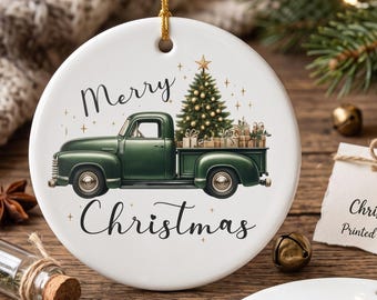 May include: A round white ceramic ornament featuring a green vintage truck carrying a Christmas tree and gifts, with the text Merry Christmas. A second blank white ornament and a small tag labeled Ceramic Christmas Keepsake are also present.