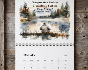 May include: A wall calendar for January 2027 featuring a watercolor illustration of a person fishing by a lake. The text reads, "Everyone should believe in something. I believe I'll go fishing." by Henry David Thoreau. The calendar is spiral-bound.