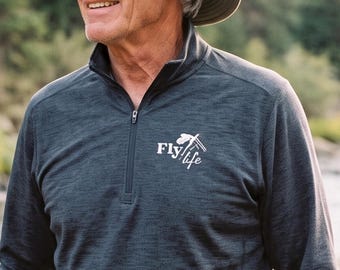 May include: A charcoal gray long-sleeve quarter-zip pullover featuring the white text Fly life with a fishing rod graphic on the chest. The garment is paired with a wide-brimmed olive green sun hat with a mesh ventilation band around the crown.