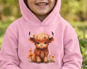 May include: A light pink hooded sweatshirt featuring a graphic illustration of a brown Highland cow calf with small horns, surrounded by orange and yellow flowers. The long-sleeved pullover has a front kangaroo pocket and a matching hood.