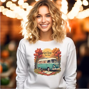 Puede incluir: Sudadera blanca con un gráfico de una furgoneta vintage turquesa y blanca y el texto "Let's Get Lost This Fall". El diseño incluye follaje de otoño y una manta de picnic. La sudadera es de estilo casual y cómodo.