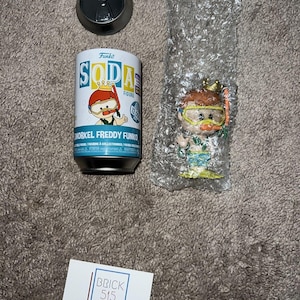 Puede incluir: Un coleccionable de Funko Soda Figure con Snorkel Freddy Funko en una lata de refresco con tapa a juego. La figura está en un envoltorio de plástico protector. También hay una tarjeta de visita.