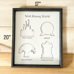 May include: Black framed wall art with a white background and cut-out silhouettes of the four Walt Disney World theme parks: Magic Kingdom, Epcot, Animal Kingdom, and Hollywood Studios. The art measures 20 inches by 17 inches.