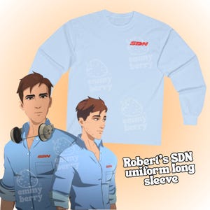 May include: Light blue long-sleeve shirt with the text "SDN" in red on the chest. The shirt has a crew neck and is decorated with white strawberry graphics and the text "emmy berry". The image also features an illustration of a man.