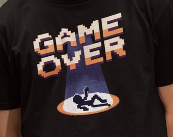 May include: Black t-shirt featuring a pixelated "GAME OVER" graphic and a pixelated figure lying on the ground.