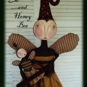 May include: A handmade doll dressed as a bee with a brown and yellow striped dress and wings. The doll is holding a smaller doll dressed as a bee. The text "Queen Bee and Honey Bee" is written above the dolls.