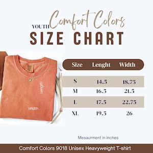 May include: A coral Comfort Colors 9018 Unisex Heavyweight T-shirt with a size chart. The chart shows measurements in inches for sizes S, M, L, and XL. The shirt has a crew neck and a tag.