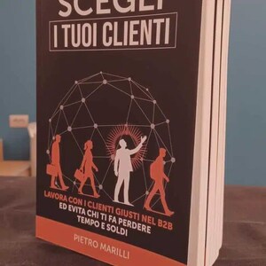 Può includere: Un libro con copertina flessibile nera che riporta il testo bianco SCEGLI I TUOI CLIENTI. La copertina mostra un grafico a rete geometrico bianco, sagome rosse di persone e il nome dell'autore PIETRO MARILLI in bianco in basso.