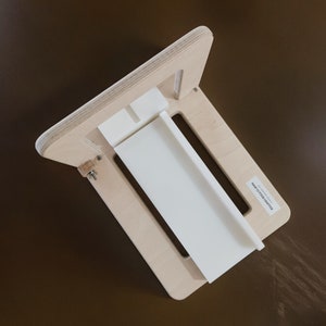 May include: A wooden soap making mould with a white plastic insert. The mould is made of light wood and has a simple design. The mould is designed to make rectangular bars of soap.
