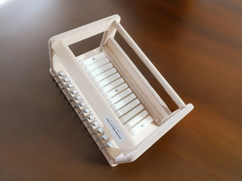 May include: A wooden soap cutter with a white plastic insert and 10 metal hooks. The soap cutter is labeled "SOAP CUTTER TRAY".