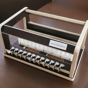 May include: A wooden soap cutter crafter with a black and white design. The crafter has a label that reads "All Natural Reed & Soap Cutter Crafter".
