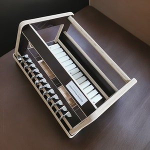 May include: A wooden guitar tuning peg holder with a black and white design. The holder has a label that says "Guitar Crafts".