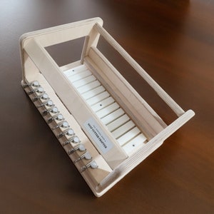 May include: A wooden soap cutter crafter with a white plastic cutting surface and 10 metal cutting blades. The text "SOAP CUTTER CRAFTERS" is printed on the side of the cutter.